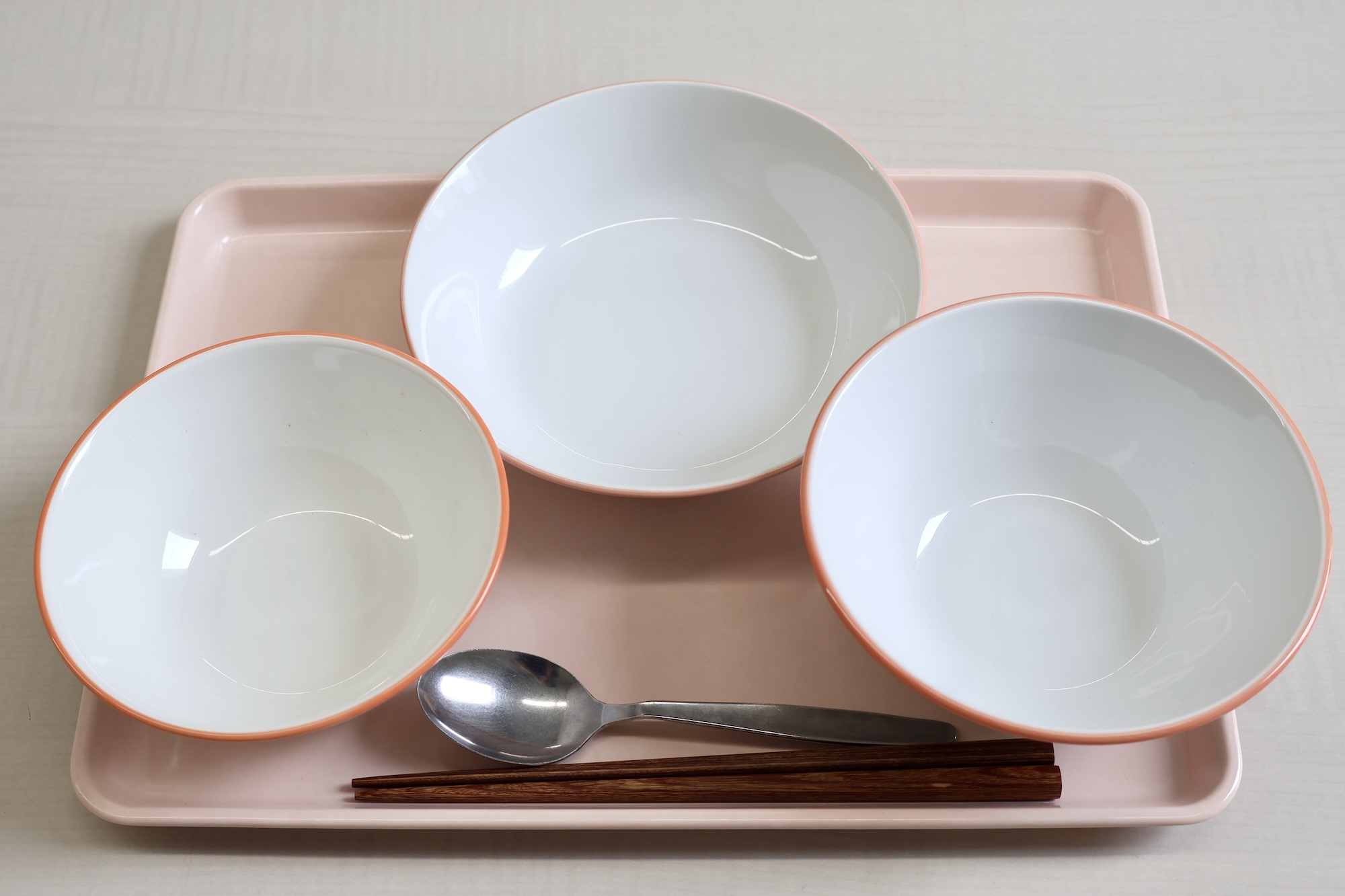 アレルギーがある児童用 ピンクのトレイ、オレンジ色のラインが入っている食器
